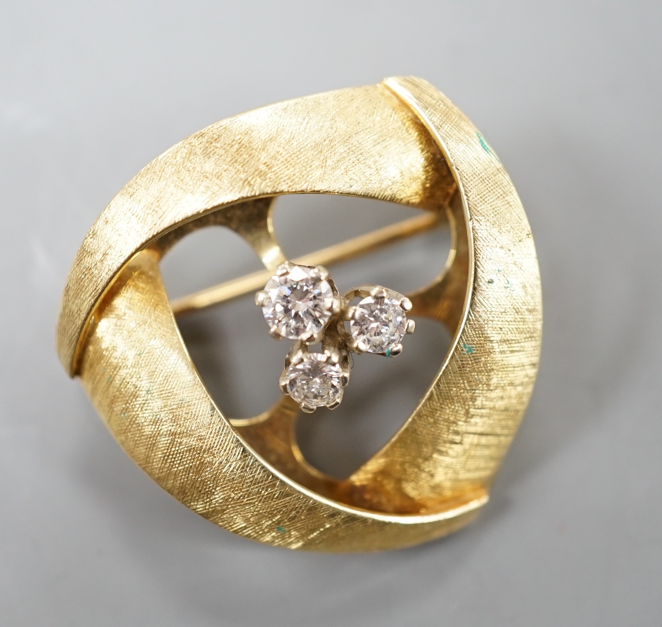 A modern brushed 14k yellow metal and three stone diamond cluster set tri-form brooch, 25mm, gross weight 7.4 grams.